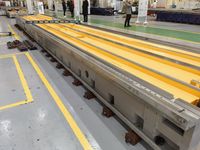 Длинная станина портального станка на монтажных опорах, на станине лежит контрольный уровень