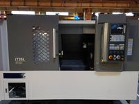 Токарный станок SMTCL iT35L, вид спереди крупным планом: серая дверь рабочей зоны, пульт ЧПУ и ниша гидравлики