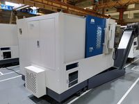 Токарный станок SMTCL iT35L в цеху завода, вид 3/4: торцевая стенка со шкафом управления, синяя дверь рабочей зоны, пульт ЧПУ и стружкотранспортёр