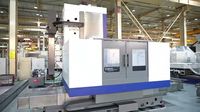 Горизонтально-расточной станок SMTCL TK(H)6513 в цеху, вид спереди: колонна с боковой бабкой, стол в белом кожухе с двумя окнами и синей полосой