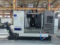 Обрабатывающий центр SMTCL VMC850B в цеху завода, вид спереди: двери рабочей зоны открыты, слева транспортёр стружки